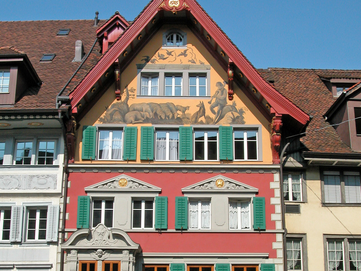 Fassadenmalerei in Mineralfarben auf Fassadenverputz. Oelfarben auf Holzwerk und Jalousien
